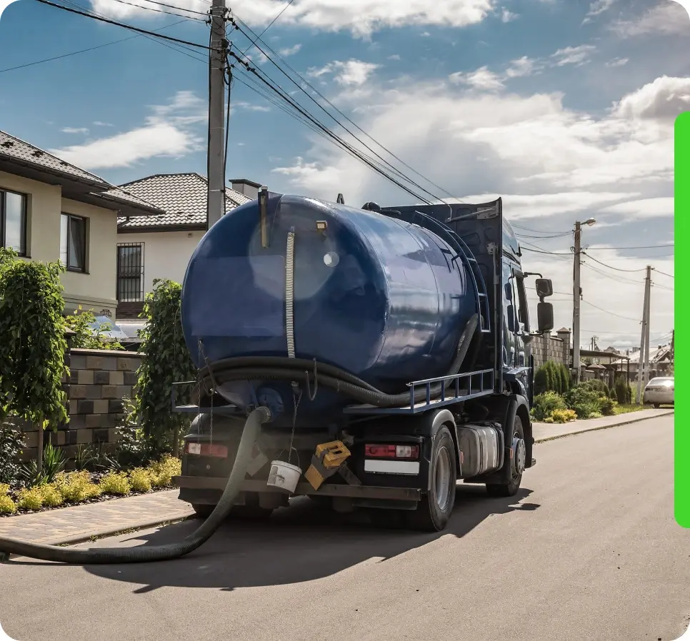 A blue sewage truck parked on a suburban street, connected to a hose leading into a house.